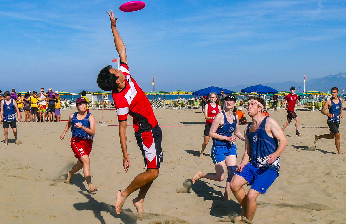 A man jumping to catch an Ultimate Frisbee on the beach